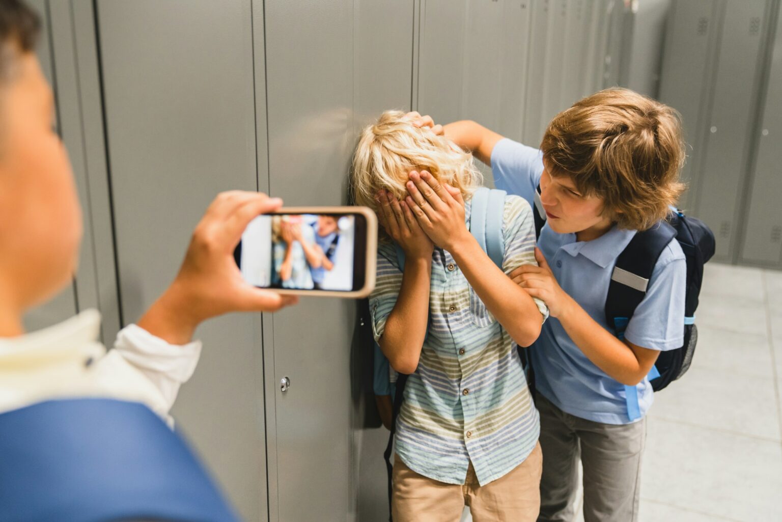 Schoolchildren cruel boys filming on the phone torturing bullying their classmate in school hall